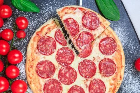 Pepperoni pizza one slice cut and rising cheese stretching golden dough, flour Stock Photos