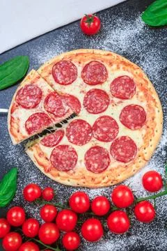 Pepperoni pizza one slice cut and rising cheese stretching golden dough, flour Stock Photos