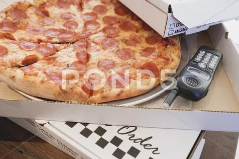 Pepperoni pizza in pizza box, telephone beside it Stock Photos