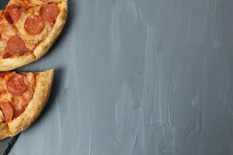 Pepperoni triangle pizza on a gray background with space for text upper angle Stock Photos