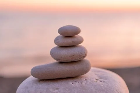 Perfect balance of stack of pebbles at seaside towards sunset. Concept of bal Stock Photos