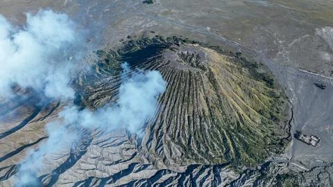 Perfect cone of volcano Batok rises dramatically from the misty plains, framed Stock Photos