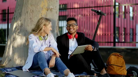 In a perfect day two students multiracial sitting down on the grass beside of a Stock Footage 138162035