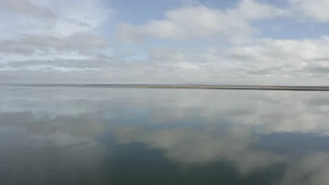Perfect mirror ocean reflecting clouds drone pull back to reveal rocks and sea Stock Footage 167482187