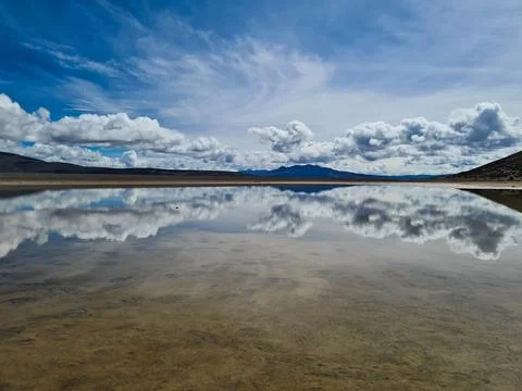 Perfect mirror reflection of sky and clouds in a high-altitude lagoon, Peru. Stock Photos