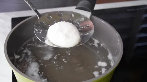 Perfect poached egg suspension over boiling water in kitchen setting.step 7 Video stock 292007261