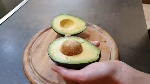 Perfect ripe avocado cut in half on a wooden cutting board Stock Footage 158662937