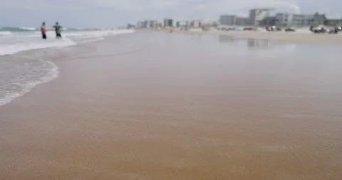 A perfect sandy beach view with ocean waves, people and buildings Stock Footage 150642723