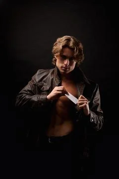 Perfect young man in unbuttoned image leather jacket showing visit card Stock Photos