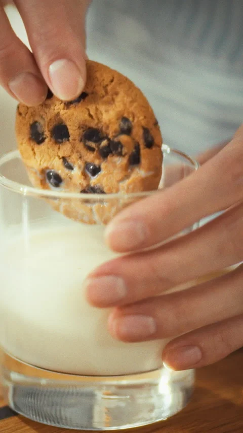 Perfectly dipping a chocolate chip cookie in milk for a cozy snack time Stock Footage 331670055
