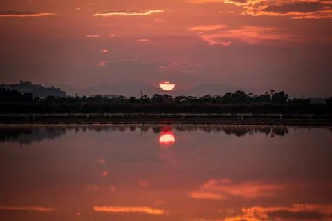 Perfectly specular reflection of the sun going down on the pond at sunset Stock Photos
