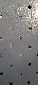 Perforated metal sheet surface with circular holes and gray paint 스톡 사진