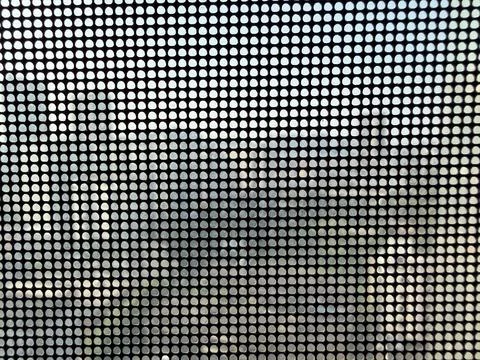 Perforated Window Screen with Blurred Outdoor View 스톡 사진