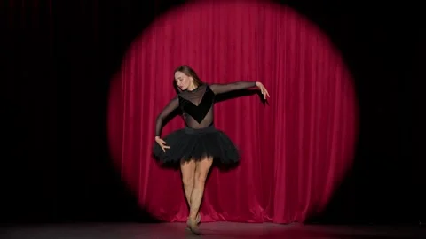 Performance, ballerina in a black tutu perform dramatic dance on a red Stock Footage 287701181