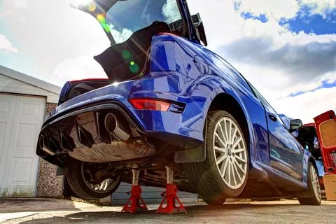 Performance blue Ford Focus RS car jacked up on axle stands in sun Stock Photos