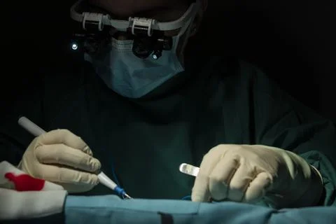 Performance of single-stremity microsurgery by a female traumatologist-surgeon. Stock Photos
