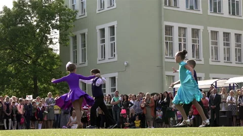 Performance of two school of dancing couples on a green grass in front of Stock Footage 65767147