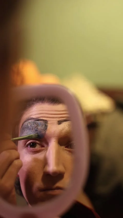 Performer applying theatrical face paint preparing for show Stock Footage 331361940