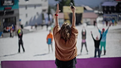 Performer in Brown Jacket Leading Crowd with Microphone at Snowy Outdoor Stock Footage 273588847