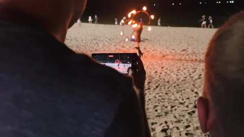 A performer with fire hoops performs for an audience on the beach. Stock Footage 317879896