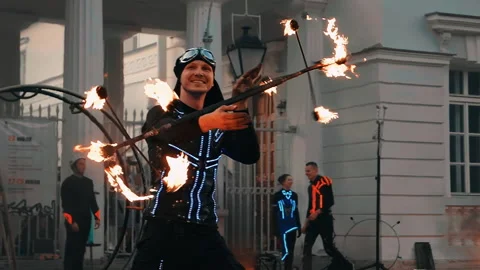 The performer of fire show spins a tripod with burning torches around the edges. Stock Footage 160804567
