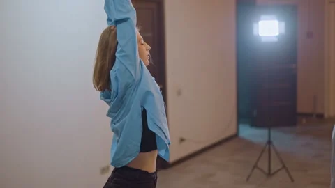Performer lifts arms in studio. Studio dancer extends arms under lights Stock Footage 346552425