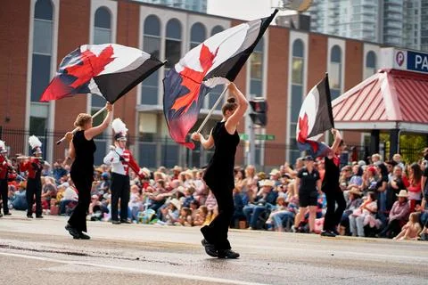 Performers wave large flags during the Calgary Stampede Parade on a lively da 库存照片
