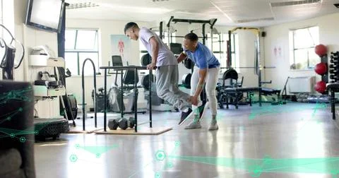 Performing client in light tee gray sweats lowering on parallel dip bars, tra Stock Photos