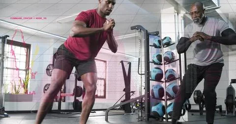 Performing lateral lunge trainee in maroon tee, black shorts at gym, med ball 스톡 사진