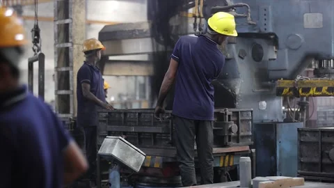 Performing sand casting operations near a massive blue molding machine Stock Footage 321741270