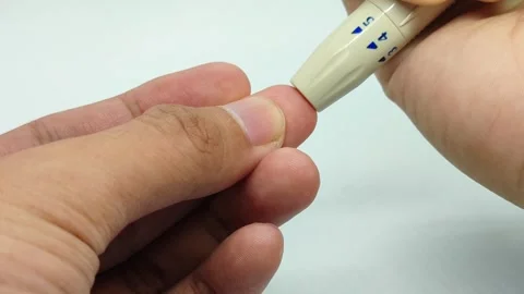 Performing a self-blood prick on the middle finger using a blood lancet Stock Footage 294426083