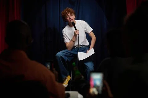 Performing Stand-Up Comedy on Stage Holding Microphone Stock Photos