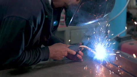 Performing a weld: the man in the welding mask is positioned with the welding Stock Footage 276084988