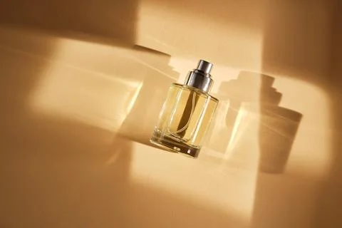 Perfume on a beige background in the rays of bright sun with beautiful high.. Stock Photos