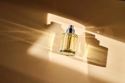 Perfume on a beige background in the rays of bright sun with beautiful high.. Stock Photos