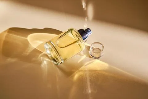 Perfume on a beige background in the rays of bright sun with beautiful high.. Stock Photos