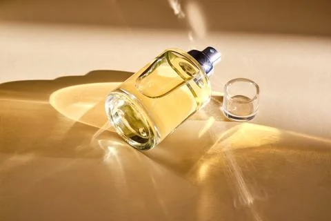 Perfume on a beige background in the rays of bright sun with beautiful high.. Stock Photos
