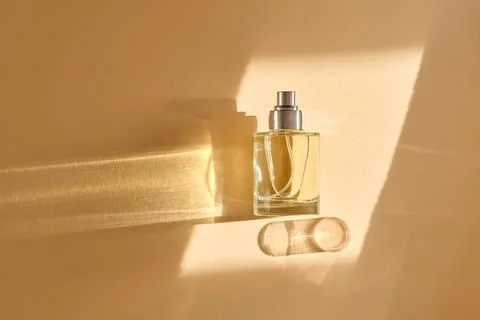Perfume on a beige background in the rays of bright sun with beautiful high.. Stock Photos