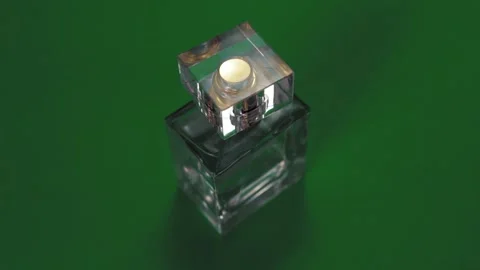 Perfume bottle and shining light flares on green background Stock Footage 147970753