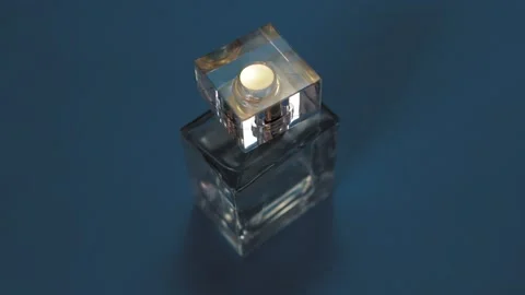 Perfume bottle and shining light flares on bright blue background Stock Footage 147971159
