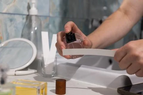 Perfume bottle being sprayed by hand onto tester strip at bathroom vanity Stock Photos