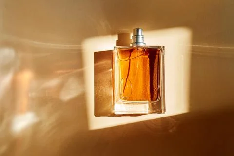 Perfume bottle capturing sunlight with amber liquid and elegant reflections Photos