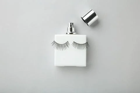 Perfume bottle with eyelashes on grey background Stock Photos