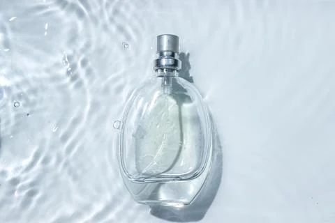 Perfume bottle on the surface of the water. Circle ripples on water surface. Stock Photos
