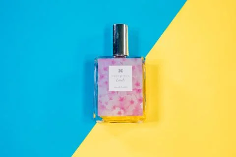 Perfume bottle on two tone solid color blue and yellow background Stock Photos
