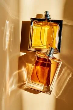 Perfume bottles reflecting warm light, concept of fragrance innovation Stock Photos
