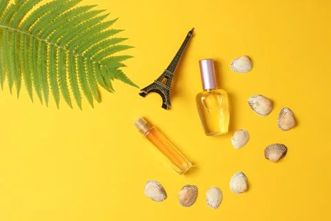 Perfume bottles, a statuette of the Eiffel Tower, fern leaf on a yellow paste Stock Photos