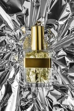 Perfume on foil background Stock Photos