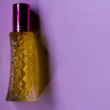 Perfume with yellow liquid on a pink solid background, watches, women's fashi Foto stock