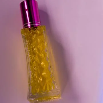Perfume with yellow liquid on a pink solid background, watches, women's fashi Foto stock